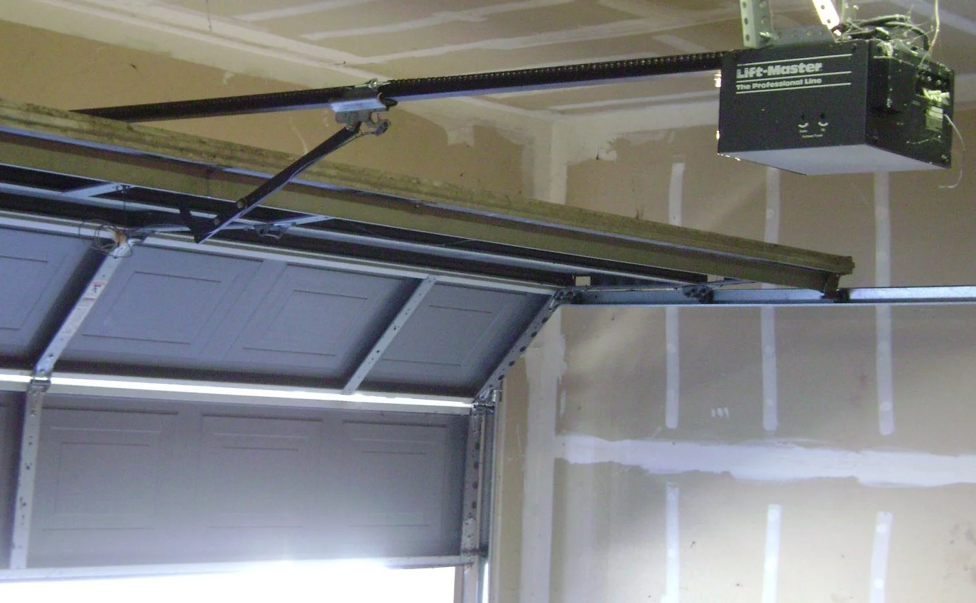 Chain-drive opener, rail and sectional garage door shown from inside a garage